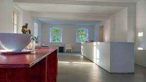 Moderni keittiö, jossa on puinen työtaso, kaksi ikkunaa, joista avautuu näkymä vehreään maisemaan, ja valkoinen keittiösaareke.