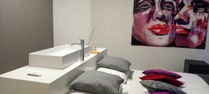 A modern bathroom with a white sink, a mirror, and a painting on the wall. - Minimalist style apartment in Upper Palatinate (Neuenburg vorm Wald)