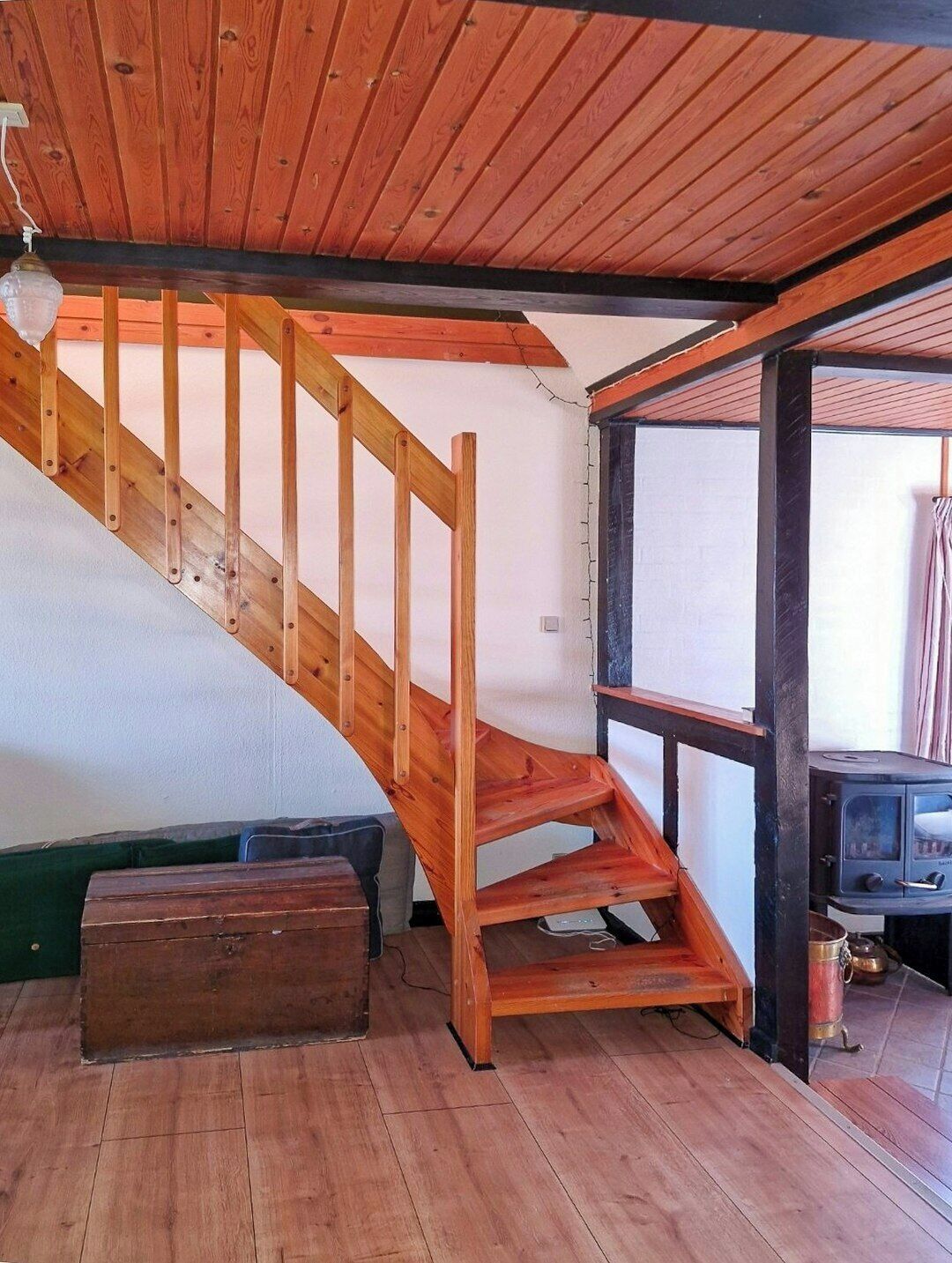 A wooden staircase leading to a loft area with a television and a stove.