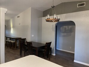A dining area with a large table and chairs, a chandelier, and a view through an archway. - Epic Pool Resort | Pickleball & Basketball Court (Fort Mohave)