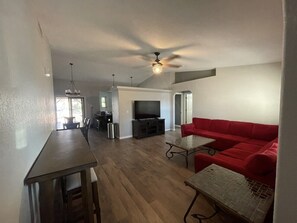 A spacious living area with a red sofa, a television, and a dining table. - Epic Pool Resort | Pickleball & Basketball Court (Fort Mohave)