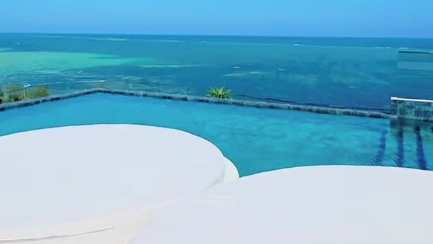 A clear view of a swimming pool with a view of the ocean and distant islands. - Hayce Residence Nyali (Mombasa)