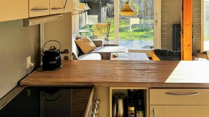 A kitchen with wooden cabinets, a kettle, and a coffee maker. - Charming family summerhouse near the beach (Højby)