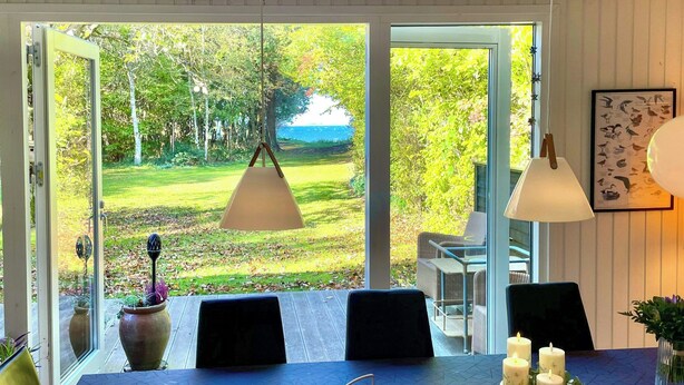 Un comedor con una mesa, sillas, velas y vistas a un jardín a través de puertas abiertas.