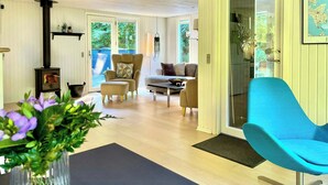 Una sala de estar con un sofá, sillones, una mesa de centro, un sillón azul, una chimenea y un ventanal grande.