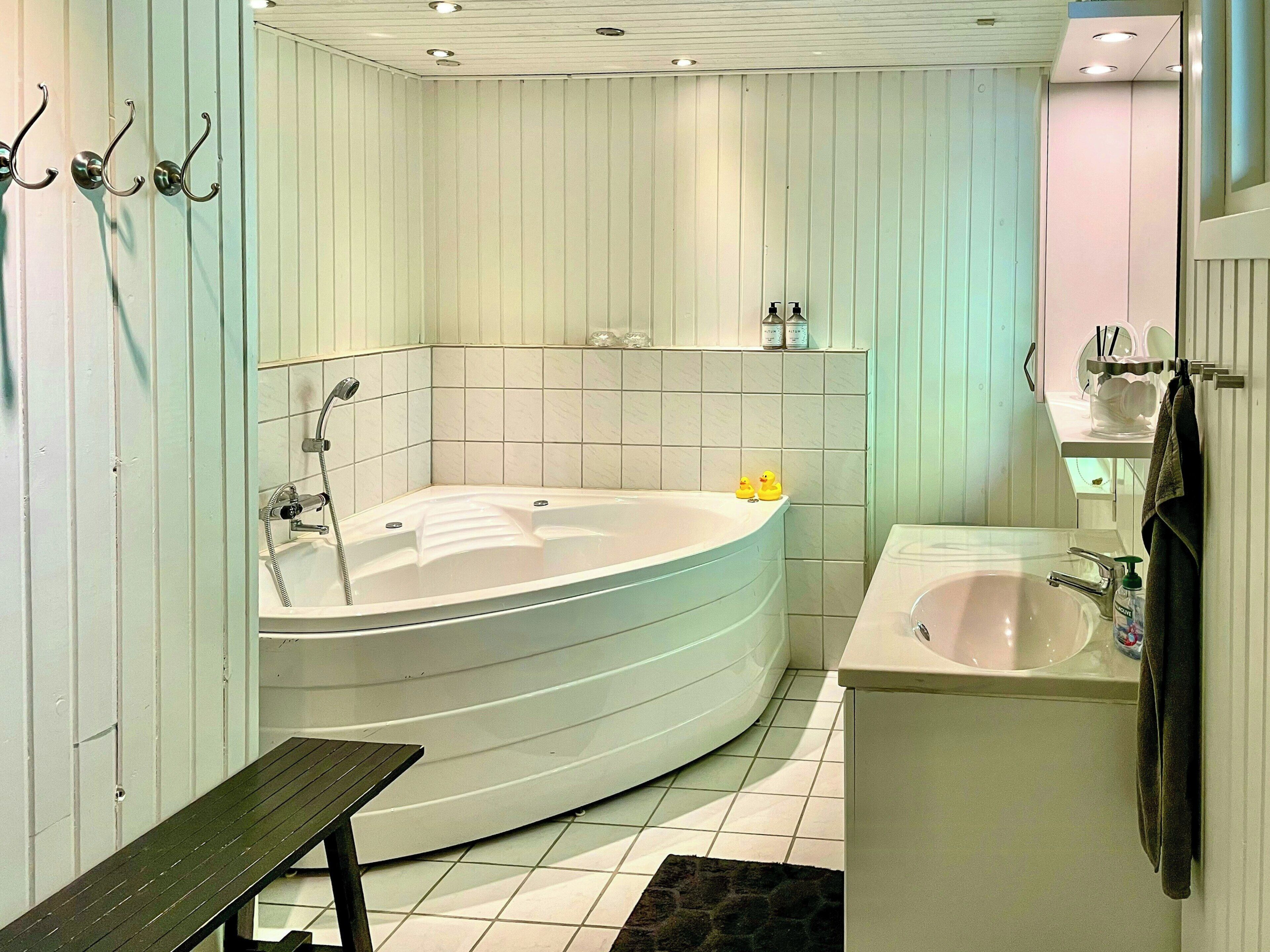 Une salle de bain avec une baignoire sur pieds, un lavabo et un banc.
