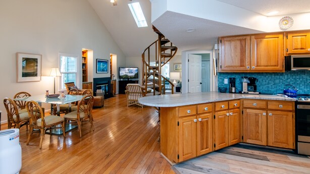 A spacious kitchen with wooden cabinets, a central island, and a spiral staircase.