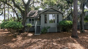 A house with a porch, surrounded by trees and a wooden fence.