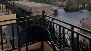 Een balkon met uitzicht op een rivier, palmbomen en verre bergen.