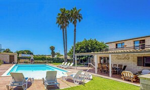 A pool area with lounge chairs, a covered patio, and tall palm trees. - Villa with ancient olive tree near Punta Secca (Kaukana, Santa Croce Camerina)
