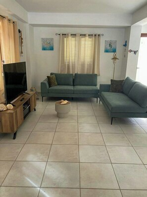 A living room with a sofa set, a TV, and a small side table. - Villa with ancient olive tree near Punta Secca (Kaukana, Santa Croce Camerina)