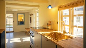 Una cocina con una isla grande, un lavamanos y una ventana con persianas.