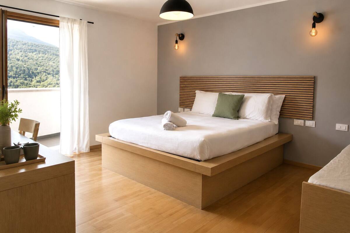 A modern bedroom with a wooden platform bed, a view of the outdoors, and a bedside table with a plant.