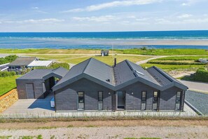 Una casa moderna con techo inclinado, ventanas amplias y vista al océano.