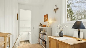 A room with a wooden desk, bookshelves, a window with a view, and a door leading to another room. - Cottage near forest and beach (Glesborg)
