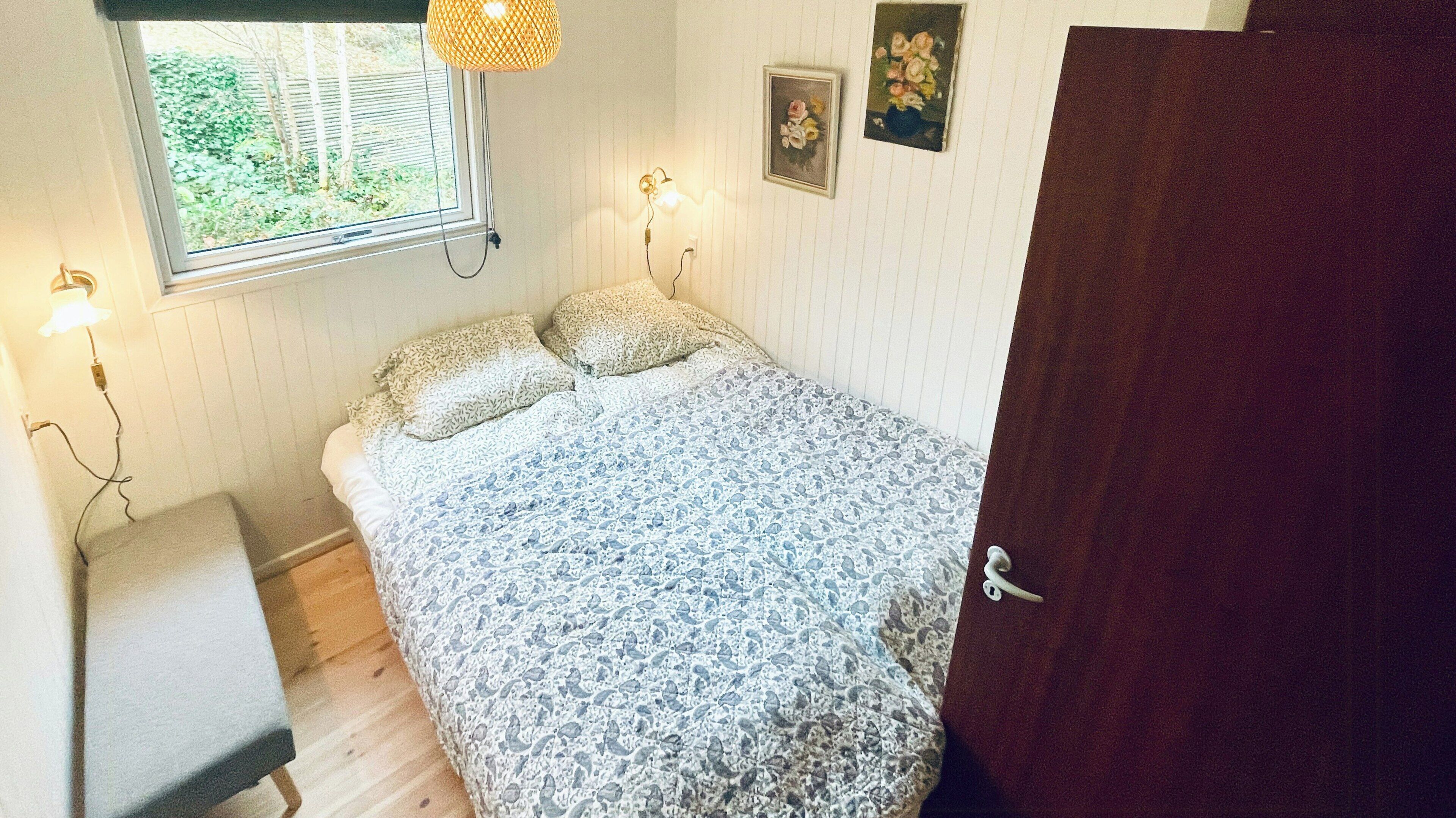 Una camera da letto con un letto, lampade ai comodini, una finestra e una porta.