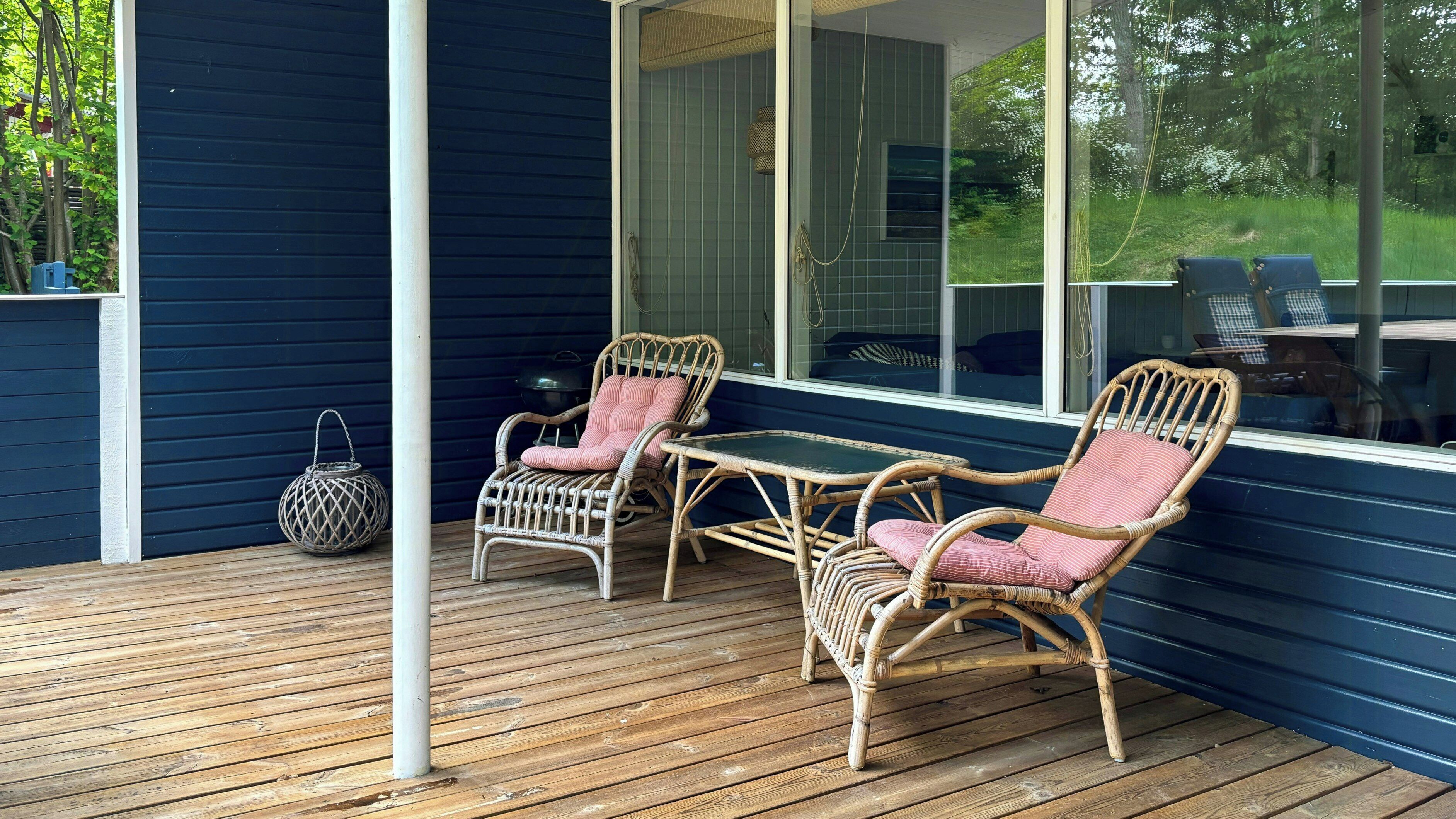 A wooden deck with wicker furniture and a large window.