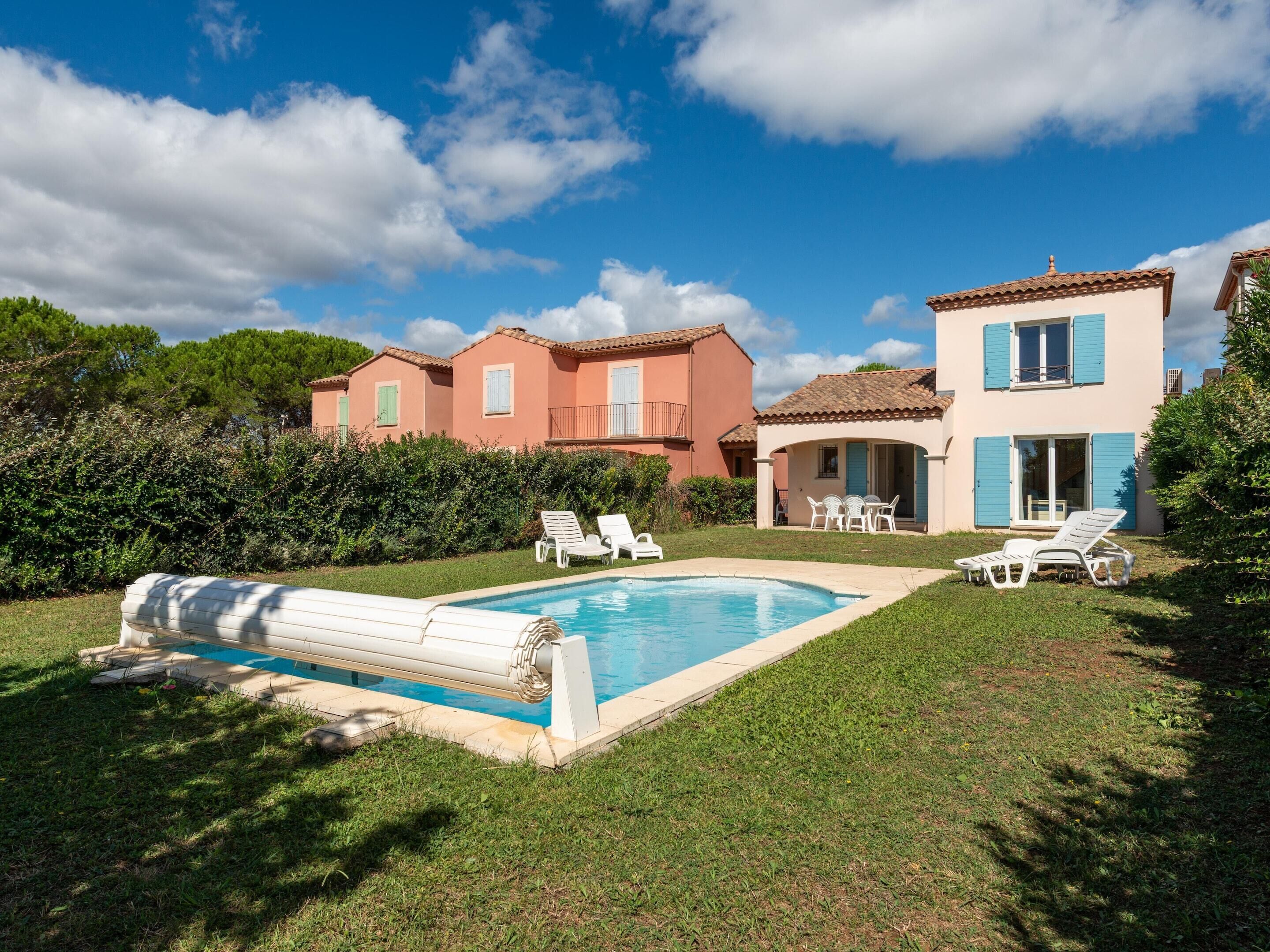 Ein Pool mit Liegestühlen, ein Gebäude mit blauen Fensterläden und ein klarer, blauer Himmel.