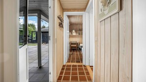 A hallway with wooden walls, a tiled floor, and a door leading to an outdoor area.