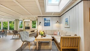 A spacious living area with a high ceiling, a skylight, a sofa, a coffee table, and a television.