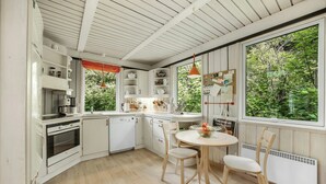 A kitchen with white cabinets, a dining table with chairs, and a window with a view of greenery.