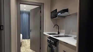 Una cocina compacta con horno integrado, microondas y refrigerador.