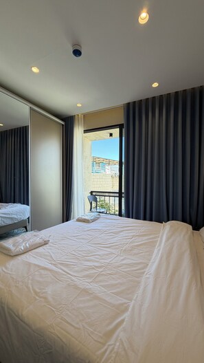 Quarto de hotel com cama, uma cadeira, janela com cortinas e vista para o exterior.
