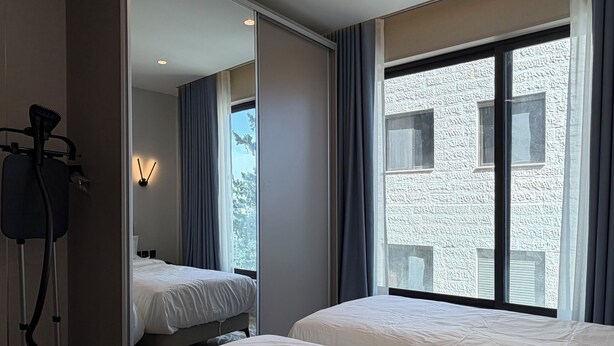 A hotel room with two beds, a hairdryer, and a mirror. - 205 tara-JRE Jabal Al Lweibdeh with stunning view (Amman)