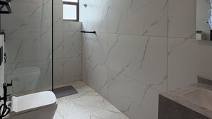 A modern bathroom with a toilet, shower, and sink, all with marble-like flooring and walls. - 205 tara-JRE Jabal Al Lweibdeh with stunning view (Amman)