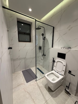 Ein modernes Badezimmer mit einer Duschkabine, einer Toilette und einem kleinen Fenster.