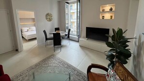 Een moderne woonkamer met een eethoek, een televisie en een groot raam.