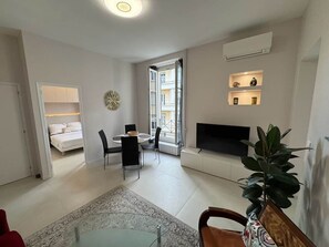 A modern living room with a dining area, a TV, and a large window. - Ambassador Promenade! (Nice)