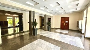 Een ruime lobby met een hoge plafond, grote ramen en een centrale kolom.