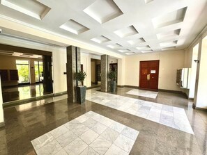 A spacious lobby with a high ceiling, large windows, and a central column. - Ambassador Promenade! (Nice)