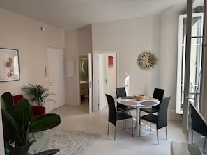 A modern dining area with a round table, black chairs, and a decorative wall piece. - Ambassador Promenade! (Nice)