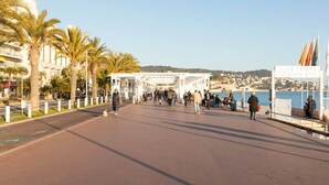 En promenade med palmer, et overdækket gangareal og et skilt der står 'LE TEMPS D'UN ÉTE'.