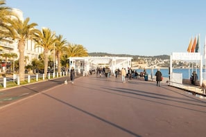 A promenade with palm trees, a covered walkway, and a sign reading 'LE TEMPS D'UN ÉTE'. - 2P Promenade des Anglais LES LIONS HA (Nice)