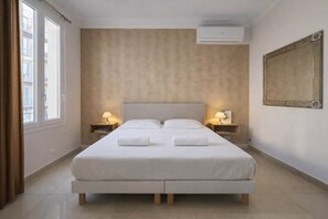 A hotel room with a large bed, two bedside tables with lamps, a large mirror, and an air conditioning unit. - 2P Promenade des Anglais LES LIONS HA (Nice)