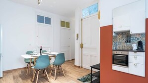 Une cuisine de taille réduite avec des meubles blancs, une machine à café et un pare-feu en carreaux.