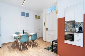 Eine kleine Küche mit weißen Schränken, einer Kaffeemaschine und einer gefliesten Spritzschutzwand.