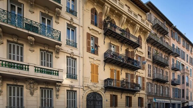 Un immeuble à plusieurs étages doté de balcons, de fenêtres en arc de cercle et de moulures décoratives.