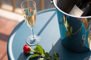 Eine Champagnerflasche, ein Champagnerglas und eine Rose auf einem blauen Tisch.