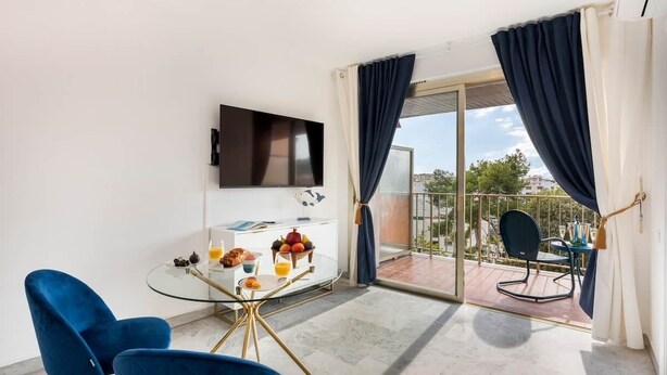 Een balkon met een glazen tafel, stoelen en een televisie.