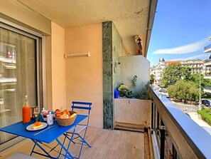 A balcony with a table set for breakfast, a bottle of orange juice, a basket of bread, and a small plant. - BLUE RIVIERA TERRACE CENTRAL TRAIN STATION (Nice)