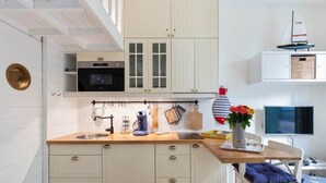 Cozinha com armários de madeira, uma máquina de café e uma pequena decoração de veleiro.