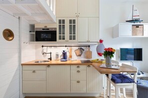 A kitchen with wooden cabinets, a coffee machine, and a small sailboat decoration. - On Board Captain – Studio cosy marin (Nice)