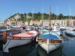 A marina with boats docked, a clear sky, and buildings in the background. - On Board Captain – Studio cosy marin (Nice)