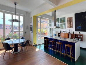 Eine moderne Küche mit Kochinsel, Barhocker und einem Essbereich mit rundem Tisch und Stühlen.