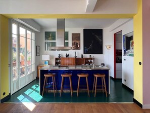 Eine moderne Küche mit Kochinsel, Barhocker und Blick durch große Fenster.