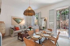 A dining area with wicker chairs, a round table set for four, and a hanging light fixture. - Home Art - Central, fantastic garden and quiet (Nice)